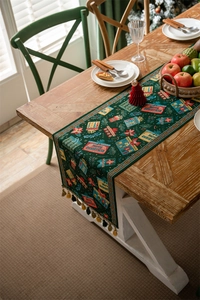 Close-up of green jacquard Christmas table runner with tassels on a wooden table