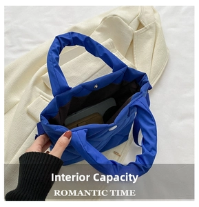 Internal view of blue quilted nylon handbag showing spacious storage capacity and magnetic clasp