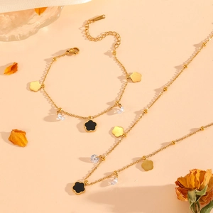 Close-up of golden stainless steel necklace and bracelet set with clover charms