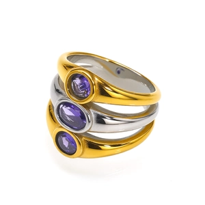 Close-up of three gold and silver titanium rings with purple gemstones and polished finish