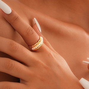 Detailed close-up of a gold-plated hollow ring with delicate pearls worn on a finger