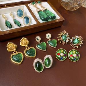 Close-up of vintage gold and green heart earrings with pearl details in a wood box