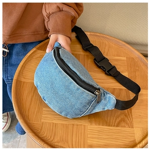 Detail of light blue denim waist bag with black adjustable strap and metal zipper