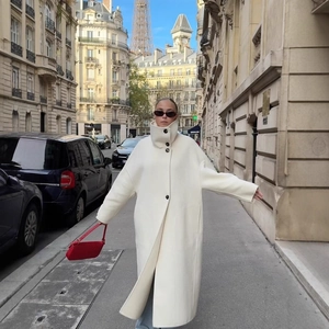 Long white stand-collar wool coat in oversized fit featuring black buttons on Paris street