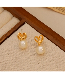 Detailed macro view of hollow heart earrings with white pearls on a beige texture base