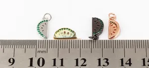 Macro shot of watermelon slice charms with green zircons and rulers for size reference