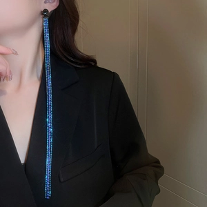 Model wearing blue-purple crystal snake chain tassel earrings on dark background