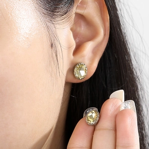 Close-up of light yellow oval faceted rhinestone earrings with silver claw setting