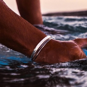 Minimalist silver stainless steel open bangle for men with ocean waves background