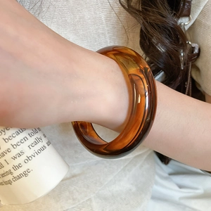 Detailed view of an amber translucent acrylic geometric cuff bangle worn on wrist