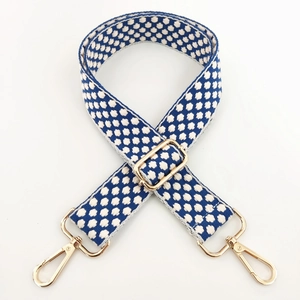 Detail of adjustable blue and white geometric embroidered shoulder strap with gold hooks