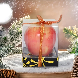 Christmas realistic apple-shaped candle in a transparent gift box with festive ribbon
