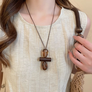 Detail view of retro resin teardrop pendant necklace on linen clothing for women