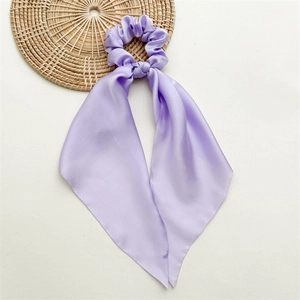 Close-up of lavender purple satin bow scrunchie with long ribbons on a minimalist background