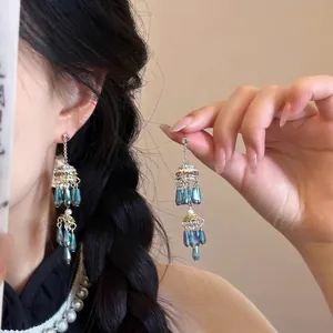 Dettaglio di orecchini boho con nappe a conchiglia, perline blu e finiture in metallo