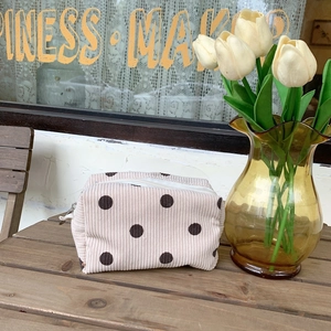 Detail of soft corduroy makeup bag with large brown polka dots on a wooden table