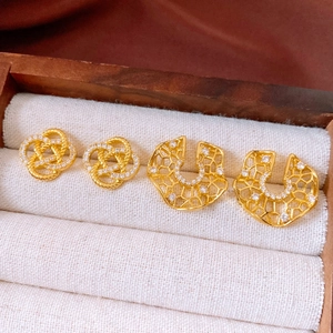 Detailed macro view of golden zircon knot stud earrings on white linen jewelry display