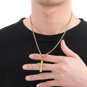 Detailed close-up of a gold cross pendant with woven chain texture on a male model
