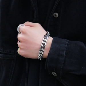 Close-up of polished silver Cuban link bracelet with spring clasp on a male wrist