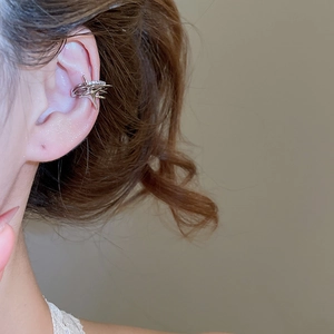 Detail view of a silver multi-layer crisscross ear cuff with zircons on model ear