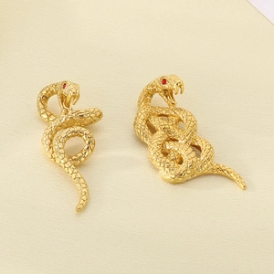 Detail of 18k gold plated snake earrings with scale texture and red crystal eyes