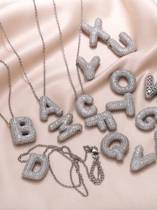 Macro detail of 3D bubble letter necklaces with sparkling zircon pavé on silk