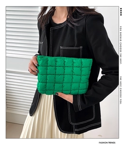 Fashionable green quilted nylon cosmetic bag held by a model against a white background
