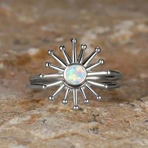 Modern sunburst ring with radiant opal stone on textured rock background
