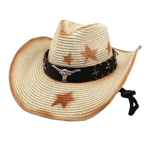 Detail of straw cowboy hat with metallic bull head emblem and vintage star pattern
