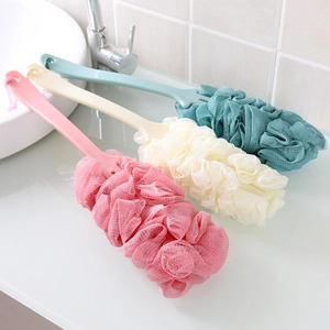 Trio of long-handle bath sponges in pink, cream, and teal on a modern bathroom sink