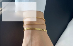 Macro view of three layered gold snake and box chains styled on a female wrist