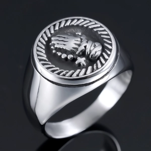 Macro shot of silver stainless steel ring featuring hands in prayer and cross relief