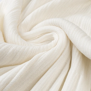 Detail shot of off-white ribbed knit fabric showing fine vertical texture and soft drape