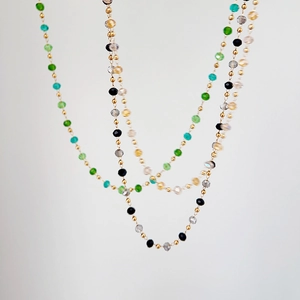 Close-up of colorful beaded necklaces with green and grey tones on 18k gold titanium chains