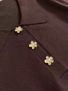 Detail of dark brown ribbed knit collar and elegant pearl flower buttons with gold finish