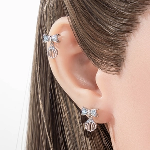 Silver bow and shell cartilage earring set with blue zircons on a female model
