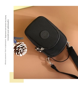 Detail of black nylon crossbody bag featuring double zipper closure and adjustable strap