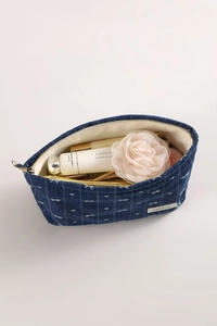 Detail of blue denim cosmetic bag showing white cross-stitch patterns and fabric interior