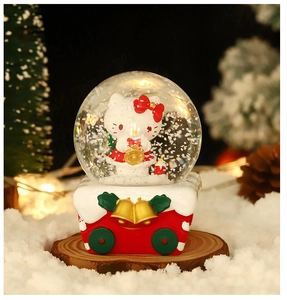 Detail shot of Hello Kitty Christmas crystal ball with warm glowing lights on wood base