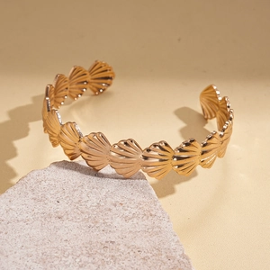 Detailed view of gold shell-shaped cuff bracelet with fine textures on stone display