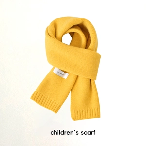 Détail d'une écharpe tricotée jaune pour enfant avec texture douce et étiquette de marque