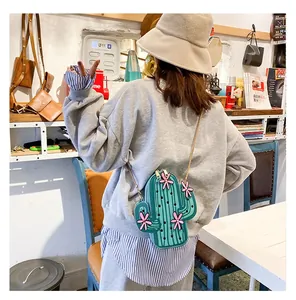 Creative green cactus crossbody bag with pink flowers and gold chain on person