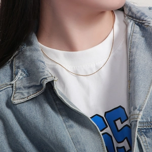 Close-up of a minimalist golden twisted snake chain necklace worn on a model's neck