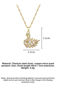 Detail shot of a golden swan pendant showing dimensions of 2.6cm by 2.2cm on a flat white surface