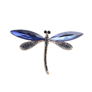 Golden dragonfly brooch featuring faceted deep blue gemstones and pavé crystal wings