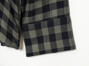 Close-up of sleeve cuff on a plaid shirt showing detailed stitching and twill fabric
