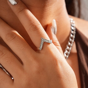 Close-up of a silver V-shaped chevron ring with sparkling crystals on a model's hand