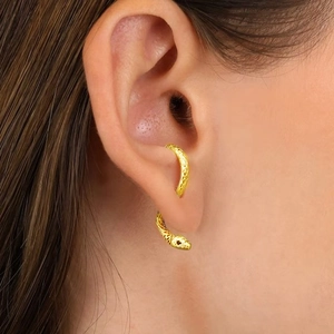 Close-up of a gold snake ear cuff with scale texture worn on a person's ear