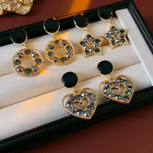 Détail de boucles d'oreilles dorées en étoile et cœur avec pierres noires en boîte