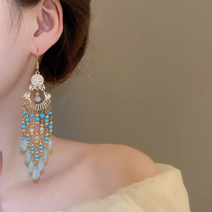 Detail of beaded tassel earring with blue beads and light green teardrop pendant
